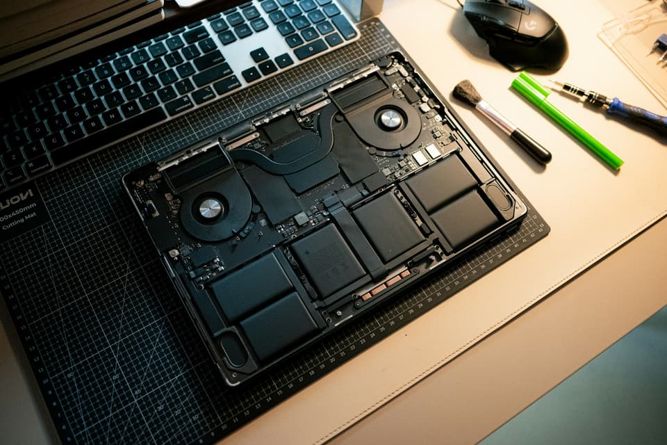 Un MacBook Pro aperto sul banco, accanto agli attrezzi di precisione