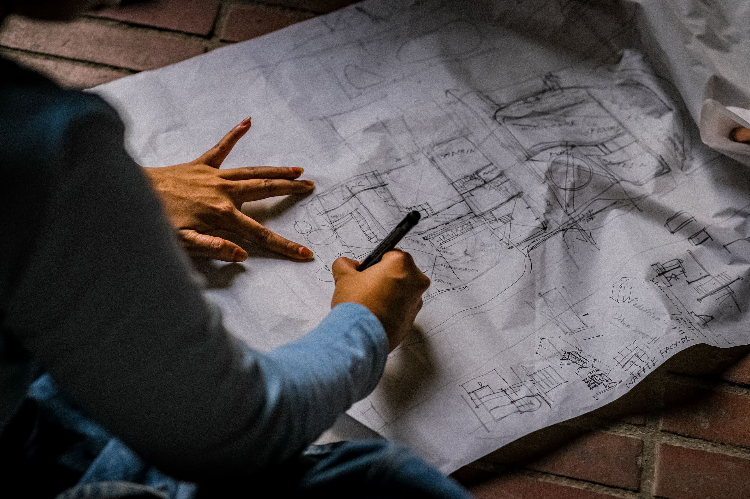Mani che disegnano a penna su una tavola di progetto