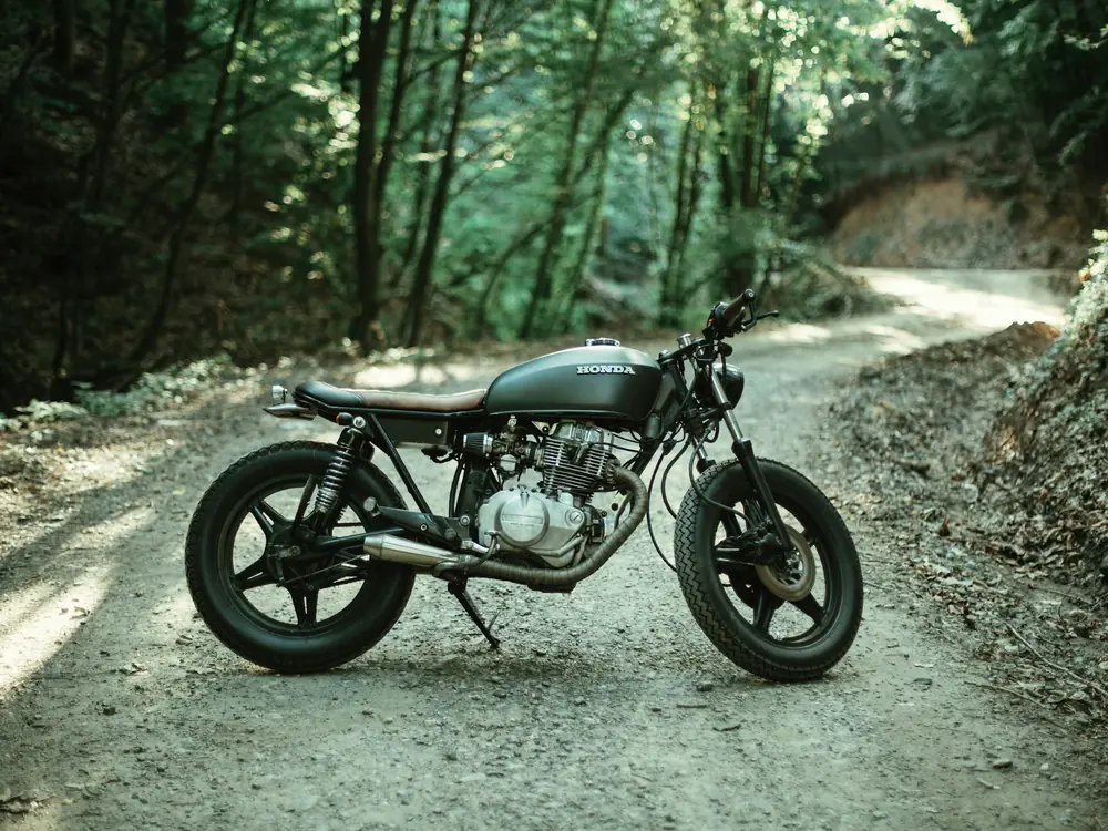 Scrambler nera su un sentiero sterrato nel bosco