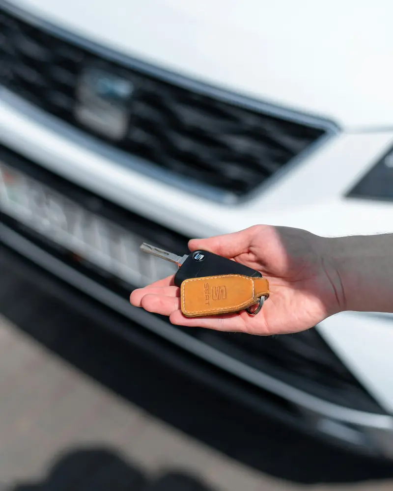 Mano che porge la chiave di un'auto davanti al cofano