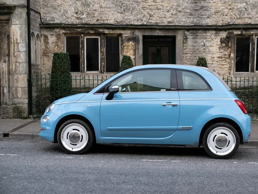 Fiat 500 azzurra parcheggiata davanti a una casa in pietra