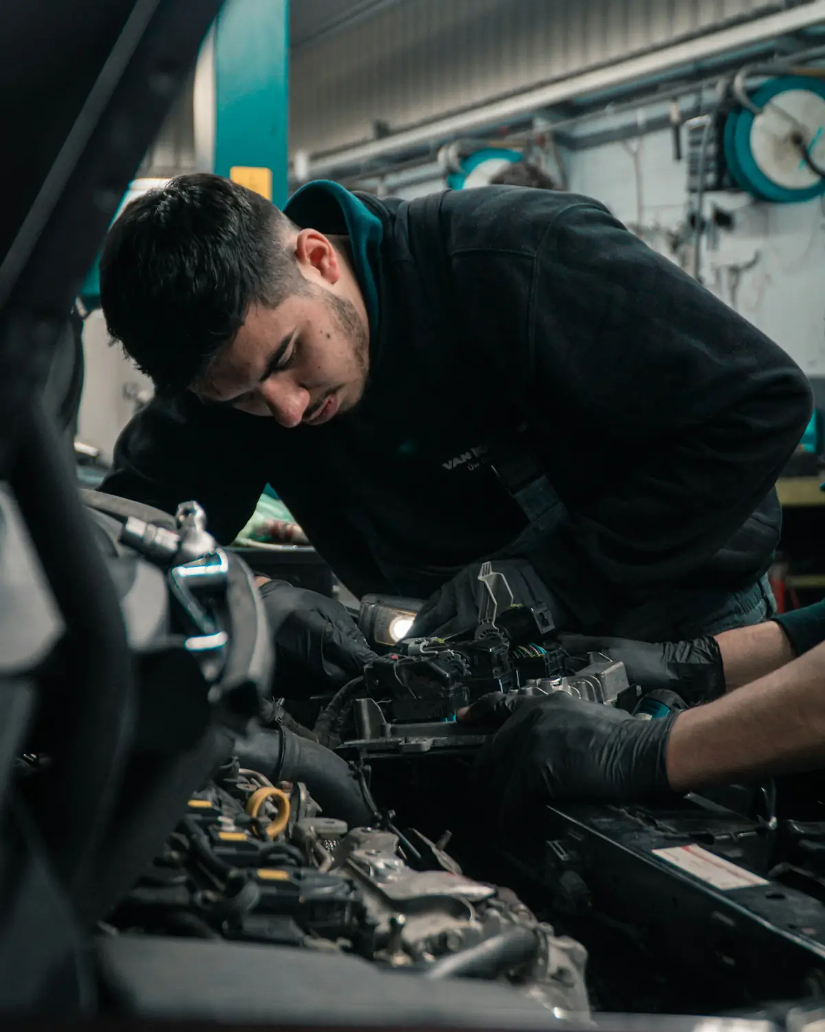 Meccanico al lavoro nel vano motore di un'auto in officina