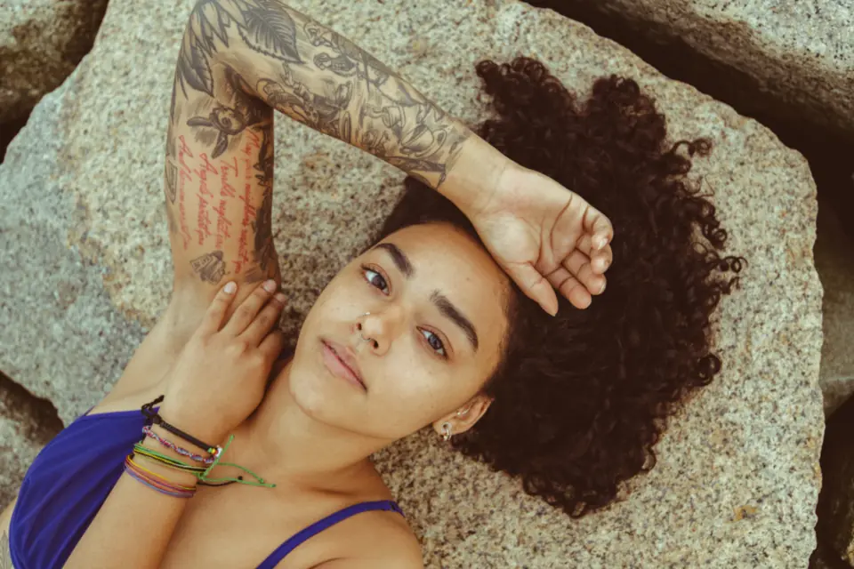 Braccio tatuato appoggiato su una roccia