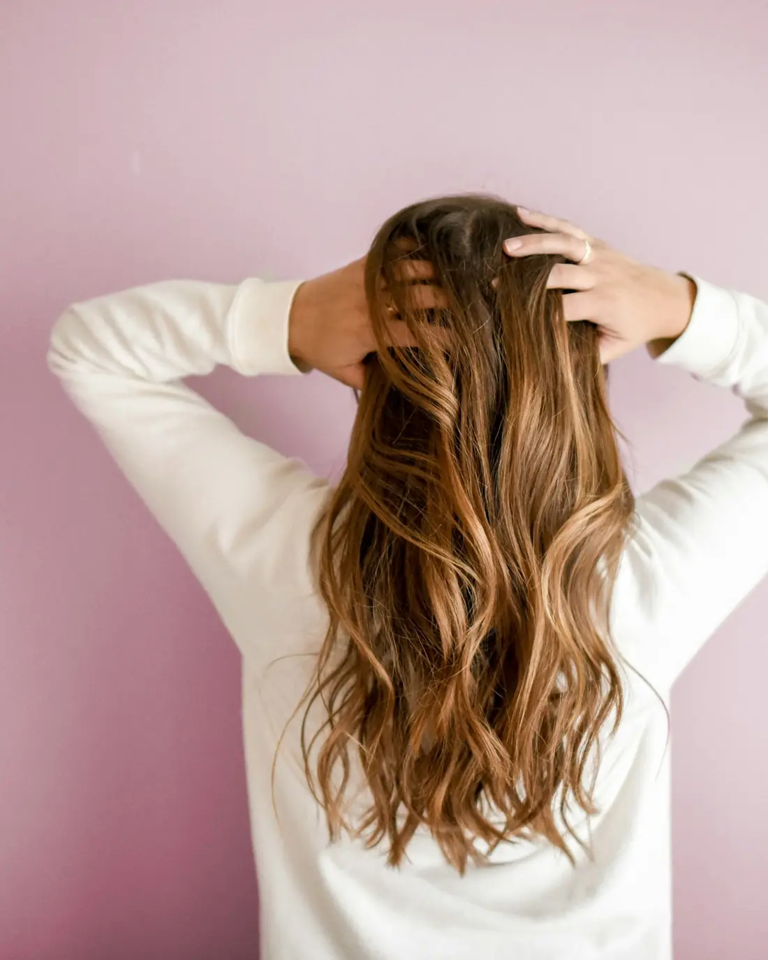 Capelli lunghi e mossi dopo la piega, su sfondo rosa