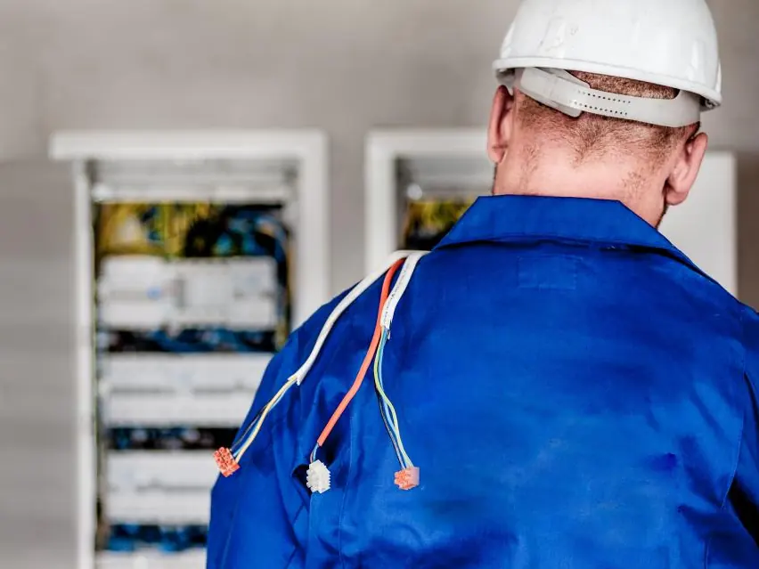 Tecnico davanti a due quadri elettrici aperti