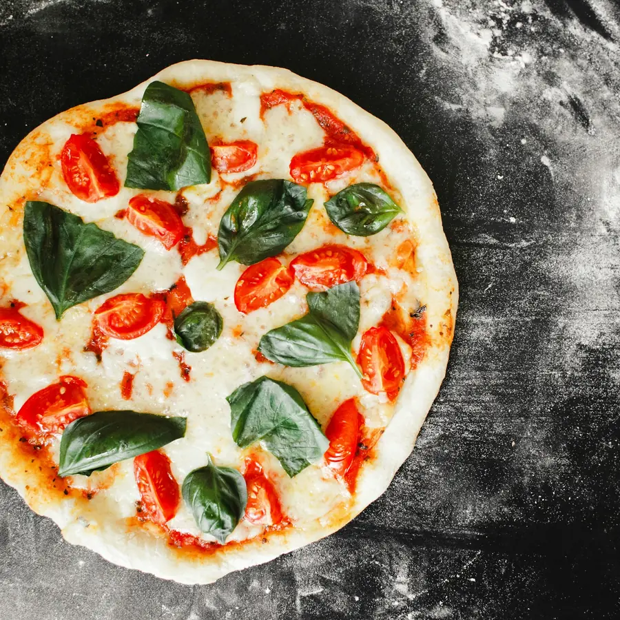 Pizza con pomodorini e basilico su piano infarinato