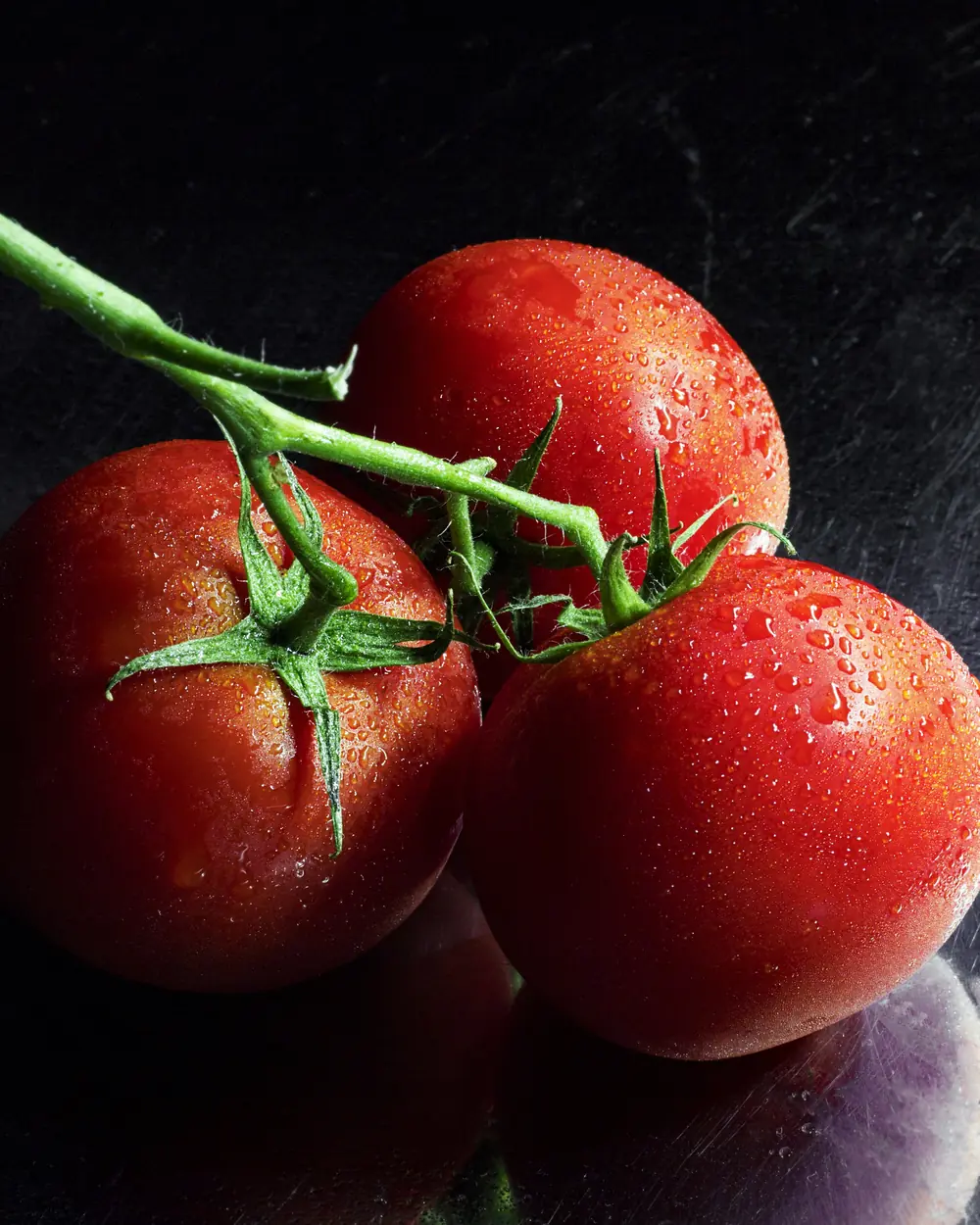 Pomodori rossi con il gambo su fondo scuro