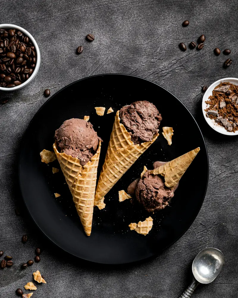 Due coni al cioccolato su un piatto scuro con chicchi di caffè