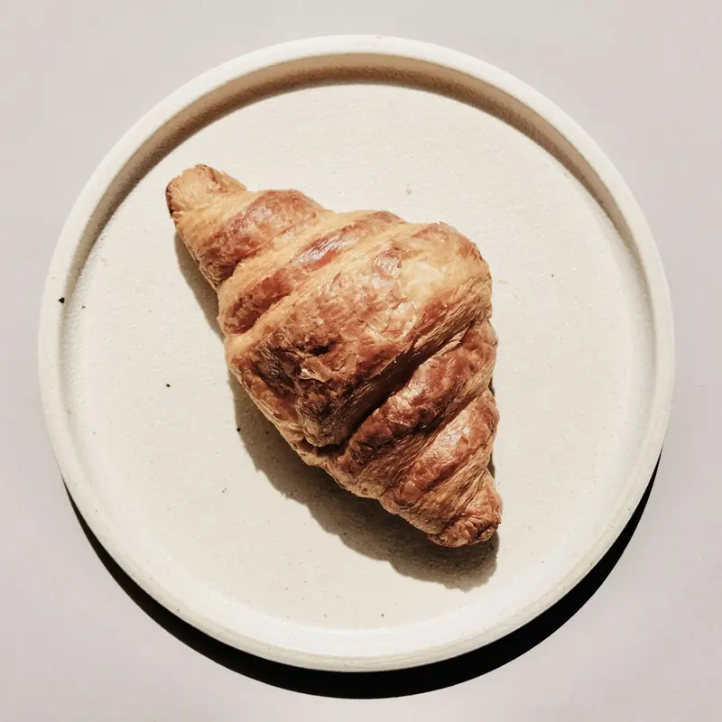 Un cornetto sfogliato su un piatto chiaro