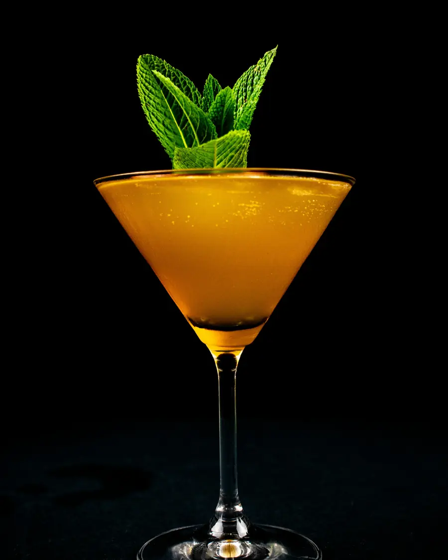 Cocktail arancione con foglie di menta su fondo scuro