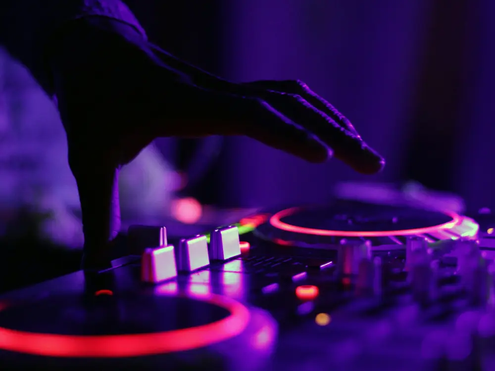 Mano sulla consolle del dj con luci viola