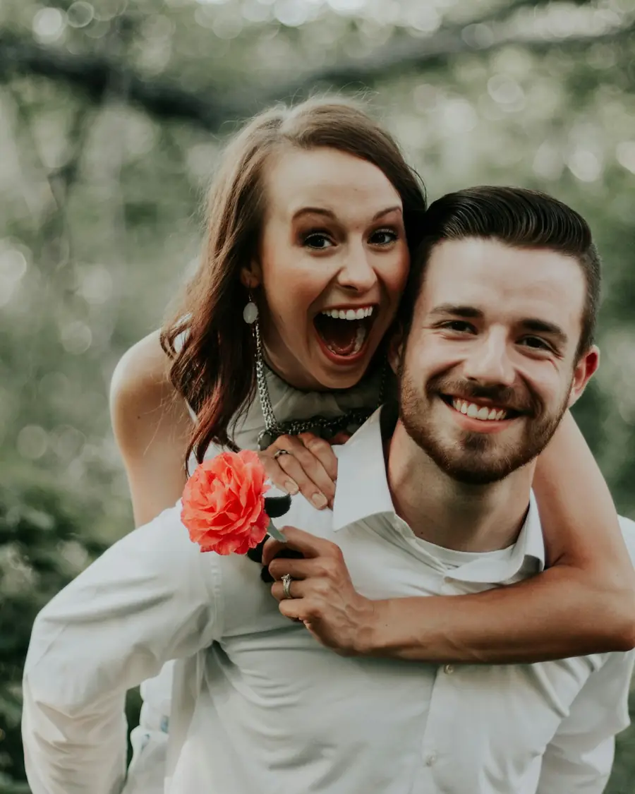 Sposo che porta la sposa sulle spalle, tutti e due ridono