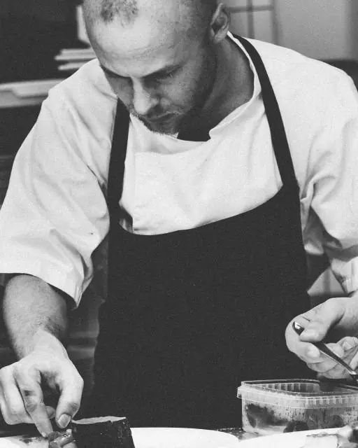 Cuoco concentrato che prepara i piatti, foto in bianco e nero