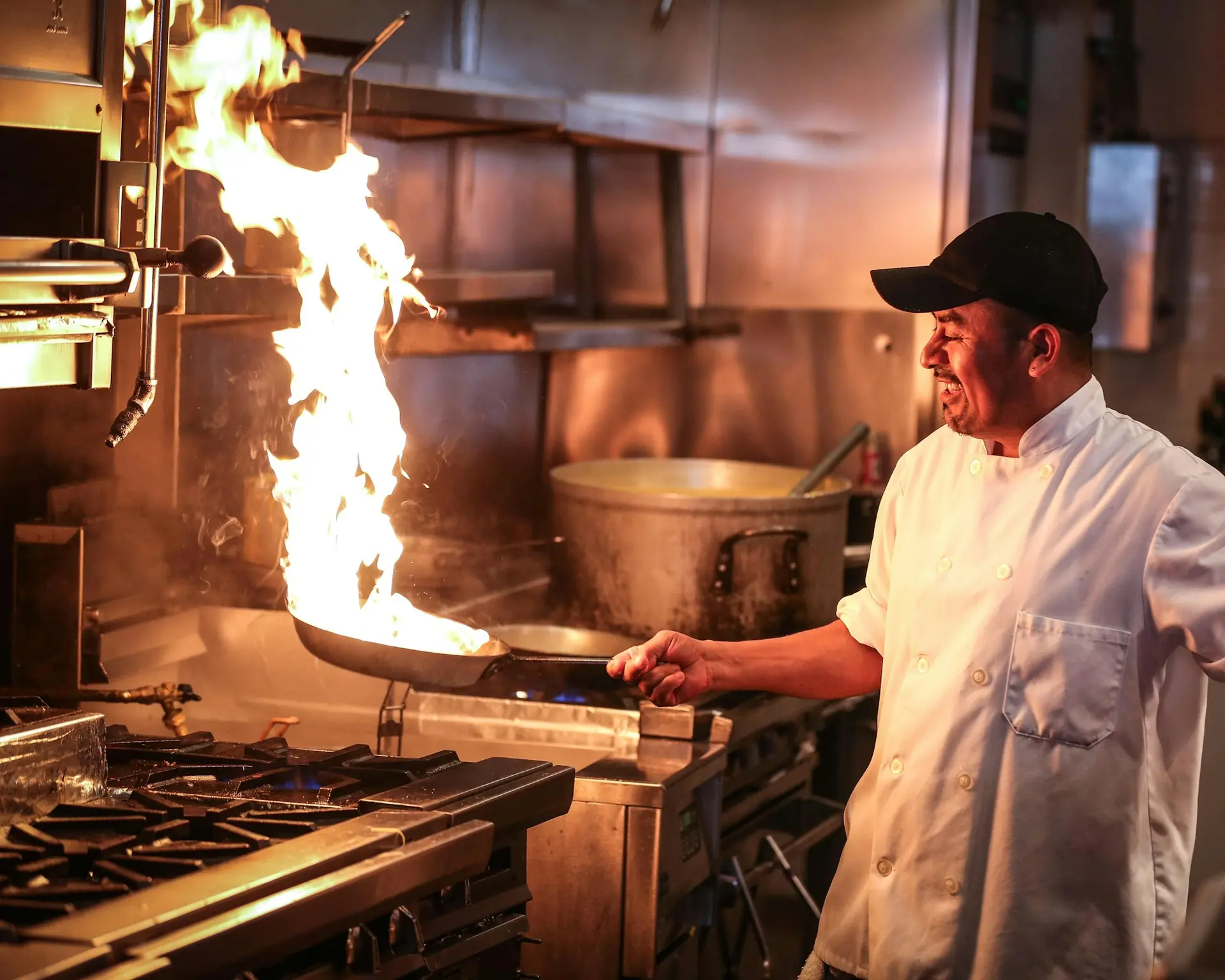 Cuoco che fa saltare la padella tra le fiamme in una cucina professionale
