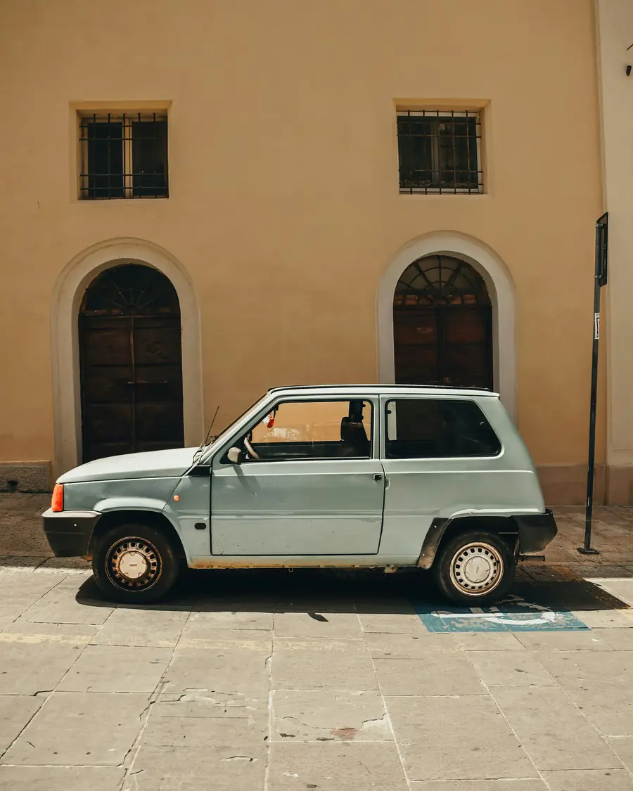 Utilitaria verde parcheggiata davanti a un palazzo giallo