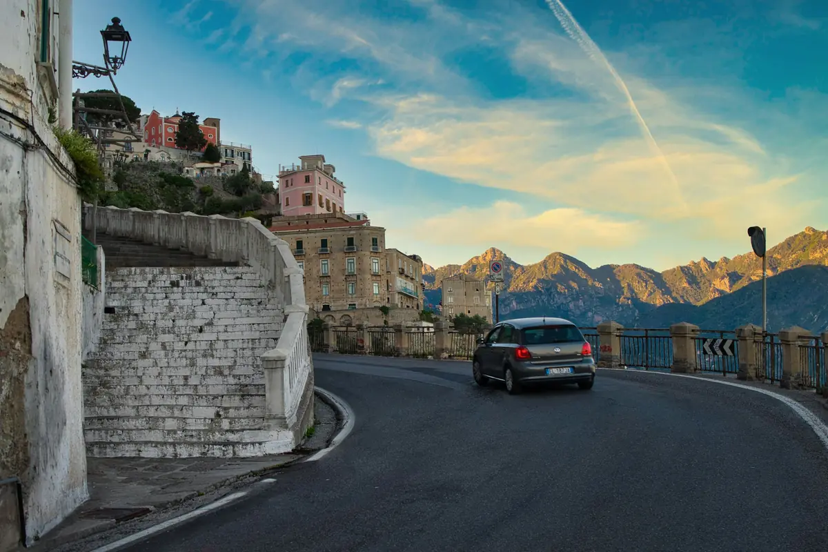 Strada extraurbana che curva lungo la costa, montagne sullo sfondo