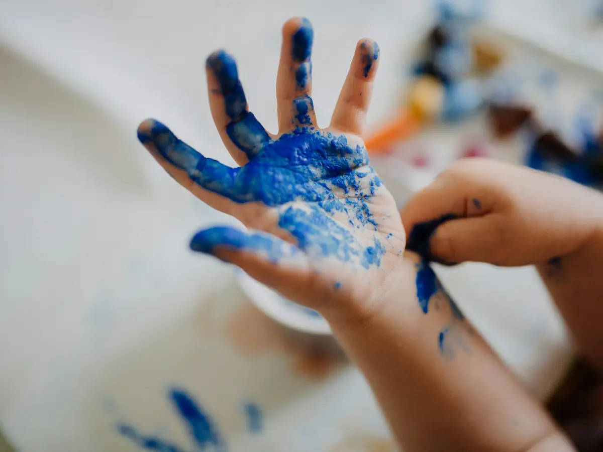 Mano di bambino sporca di tempera blu