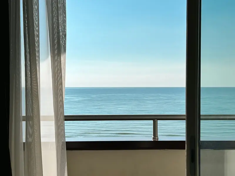 Balcone con tenda bianca e il mare all'orizzonte