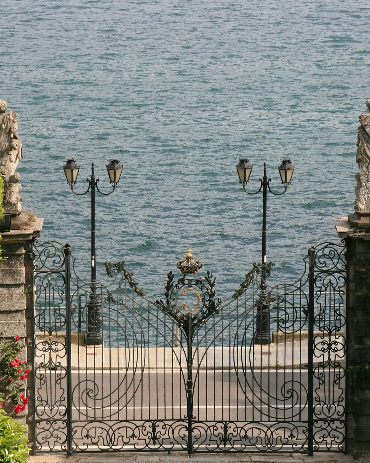 Cancello in ferro battuto tra le siepi, con il lago dietro