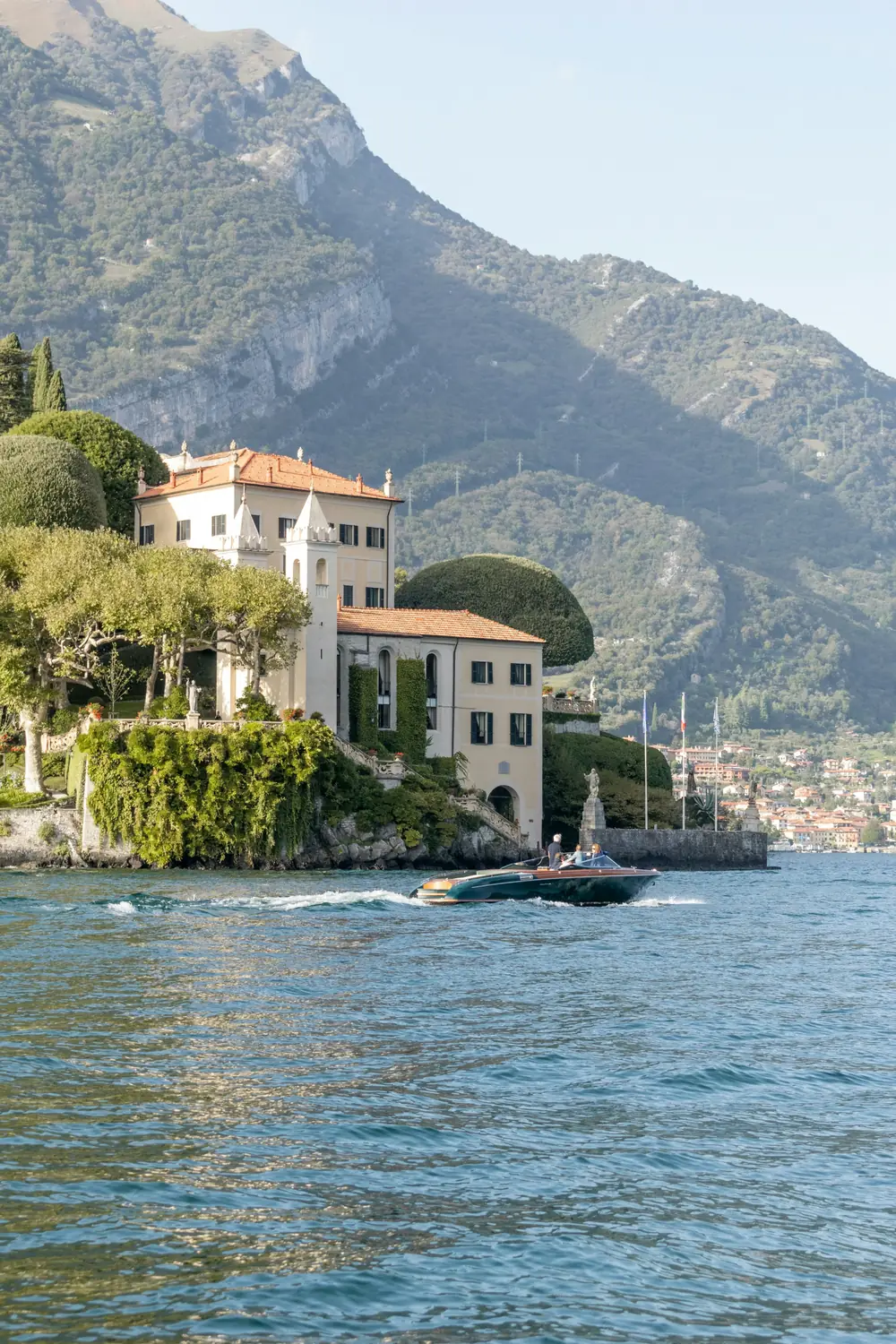 Villa sulla riva del lago con motoscafo e montagne alle spalle