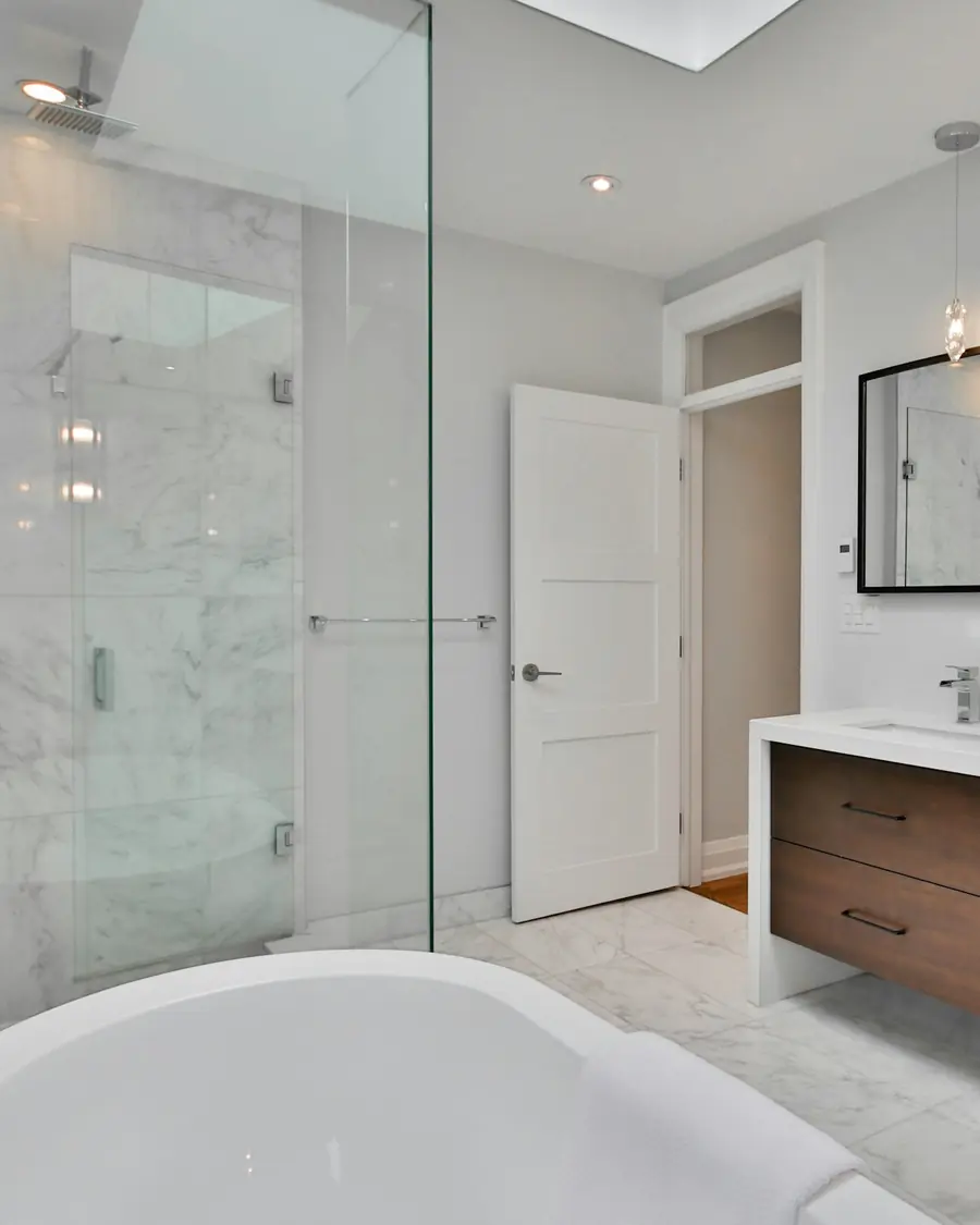 Bagno in pietra chiara con doccia a filo pavimento e doppio lavabo