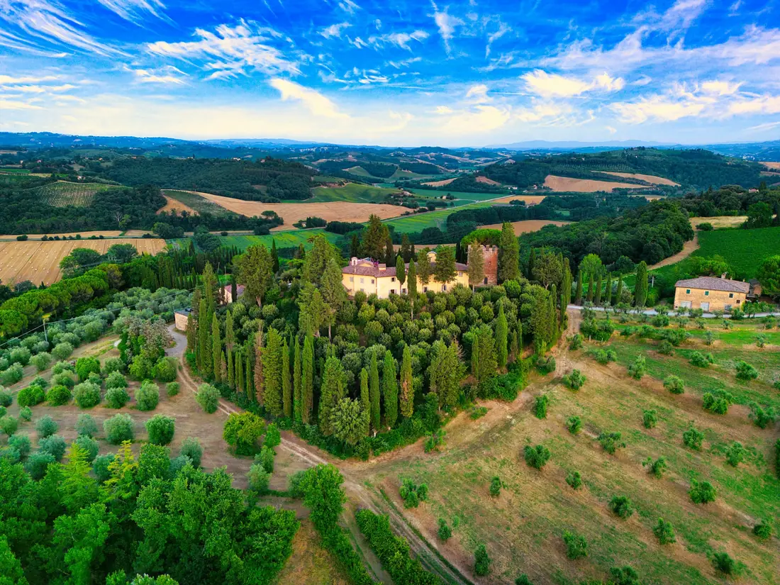 Villa tra cipressi e uliveti vista dall'alto, colline sullo sfondo