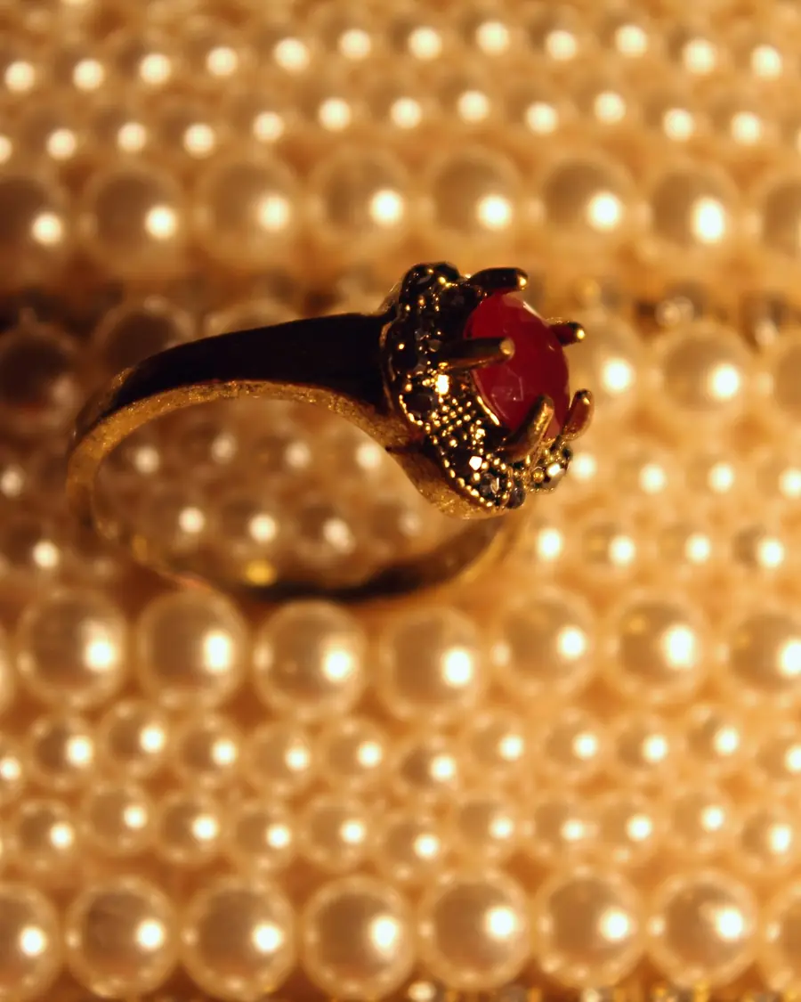 Anello con pietra rossa appoggiato su perle