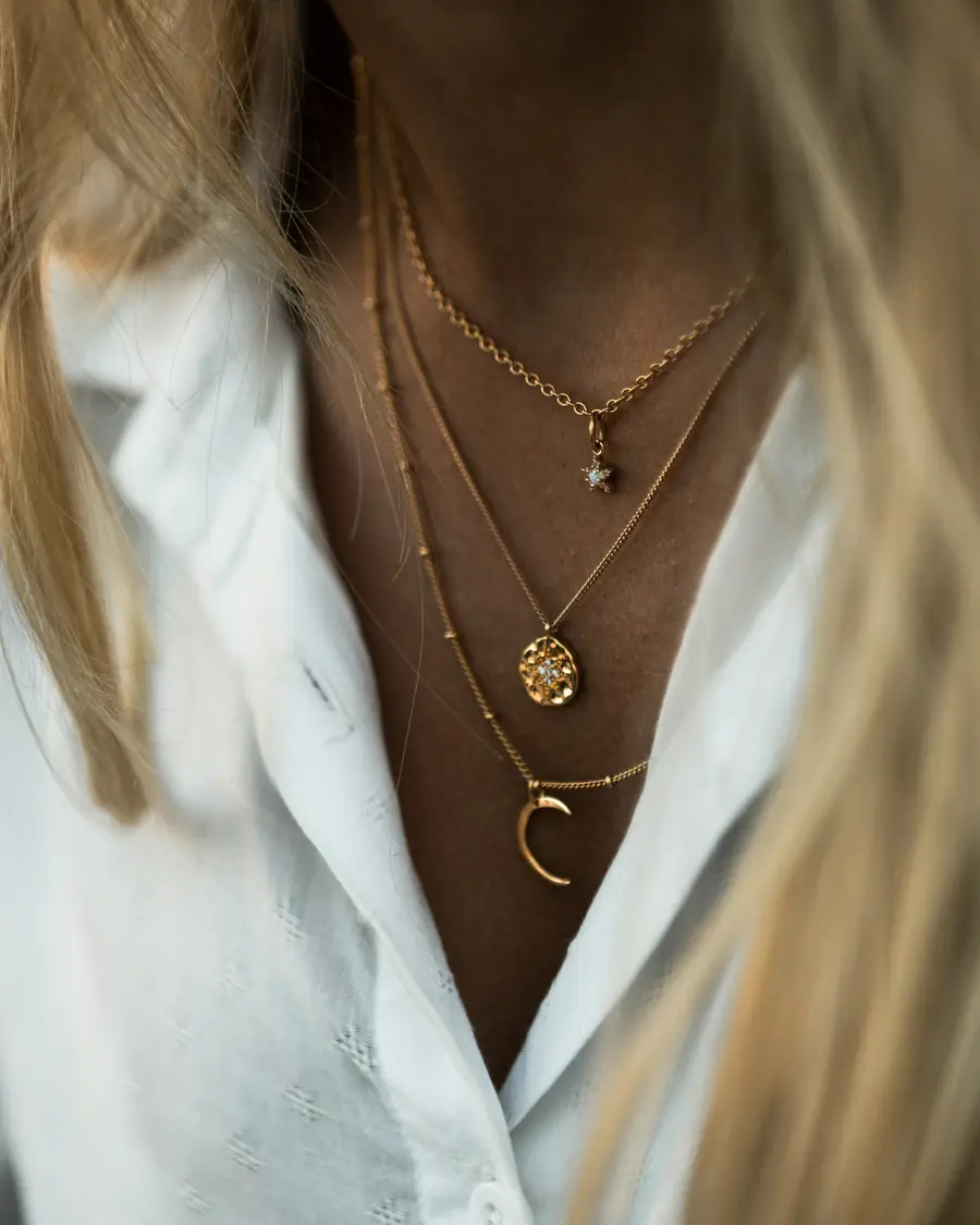 Collane sottili in oro sovrapposte su camicia bianca