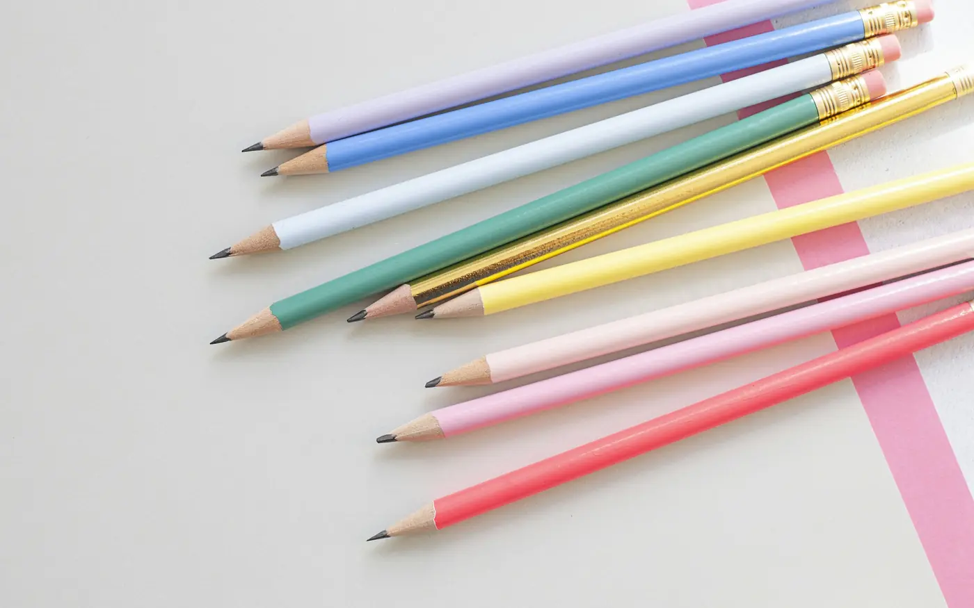 Matite colorate su un foglio bianco con una striscia rosa