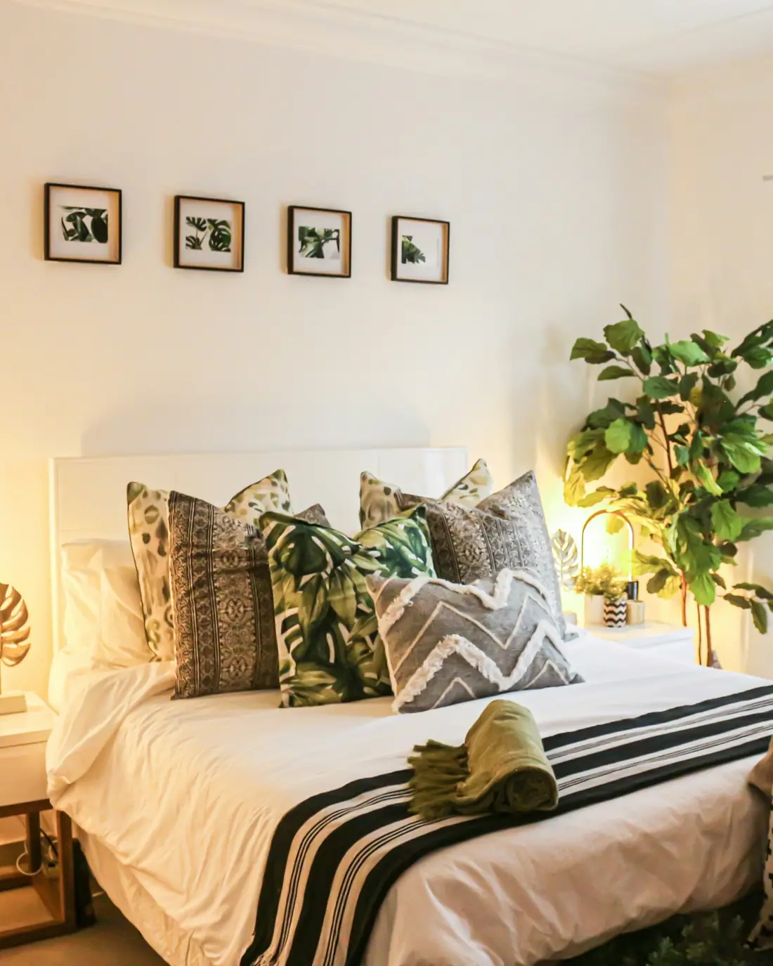 Camera con letto bianco, cuscini a righe e piante