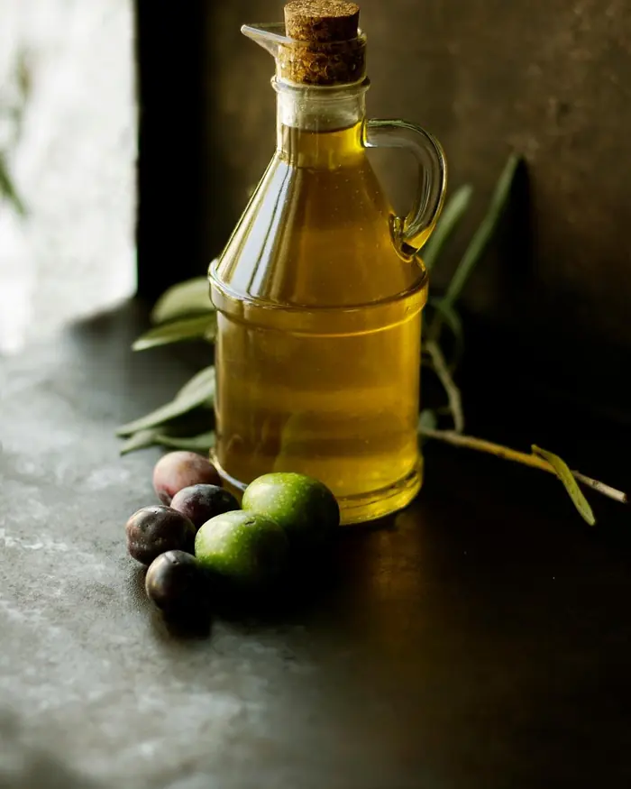 Bottiglia di olio extravergine con olive appena raccolte
