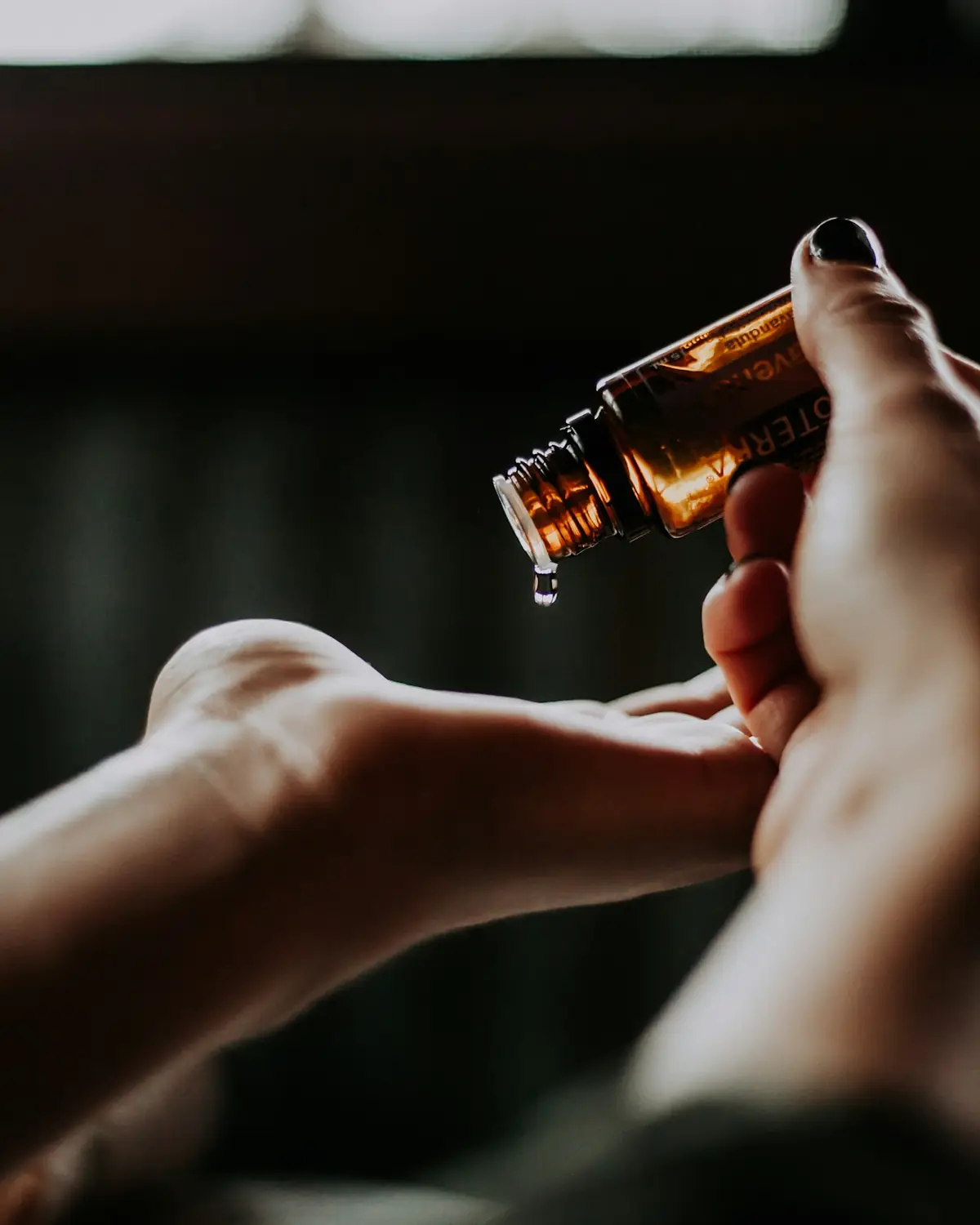Mani che versano olio da massaggio da una boccetta
