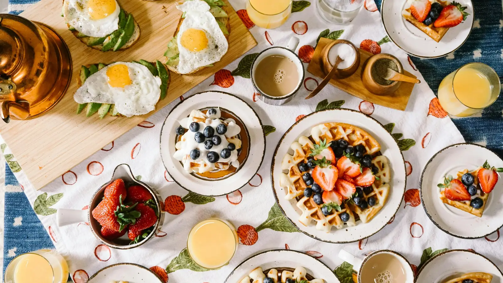 Tavola della colazione con uova, frutta, waffle e succhi