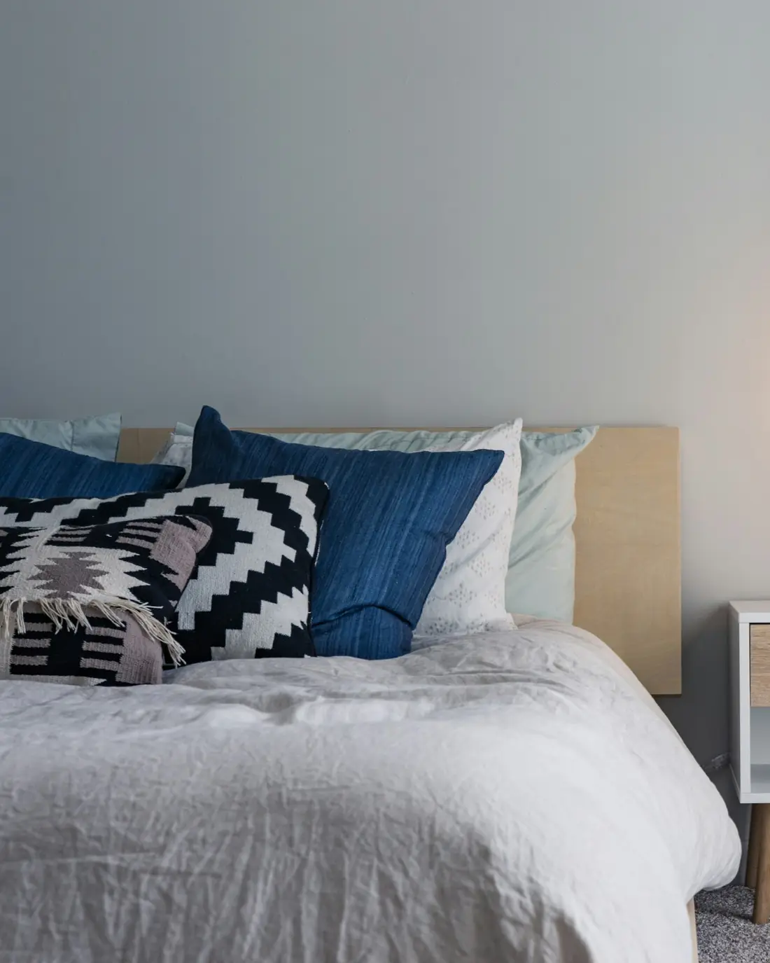 Letto con cuscini blu e bianchi e una lampada da comodino accesa