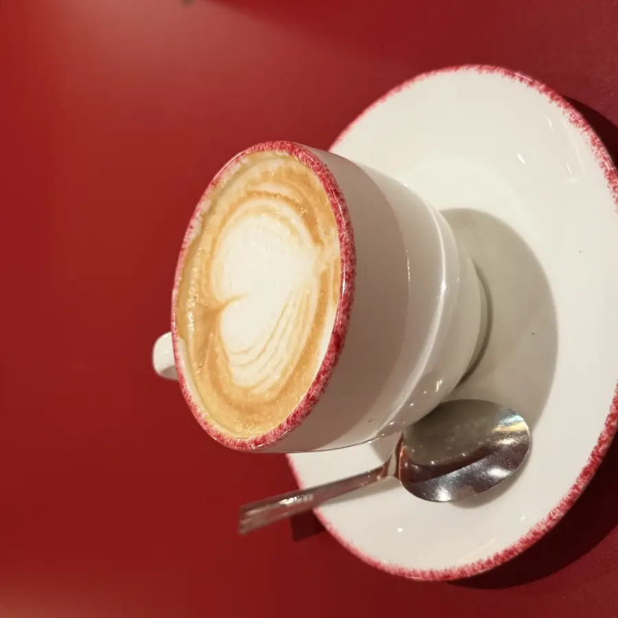 Cappuccino in tazza bianca su un tavolo rosso