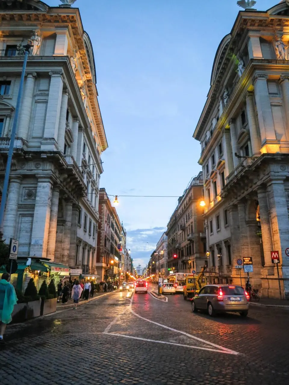 Via del centro di Roma al tramonto con i palazzi e le luci dei negozi