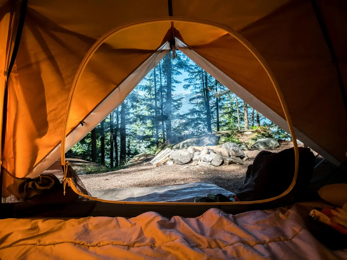 Interno di una tenda glamping aperta sul bosco