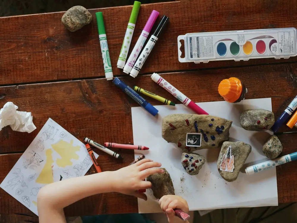 Mani di bambini che dipingono sassi con i pennarelli