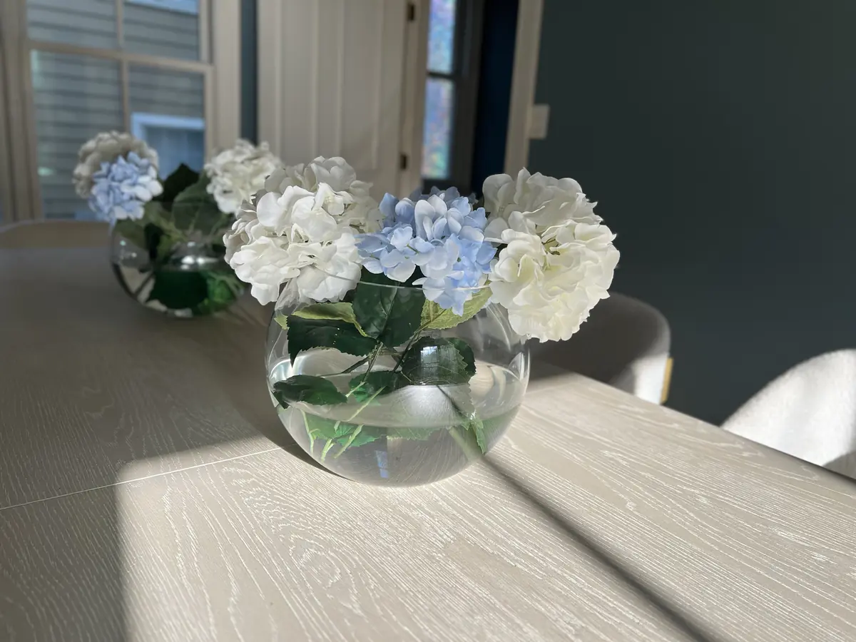 Ortensie bianche e azzurre in un vaso di vetro alla luce del sole
