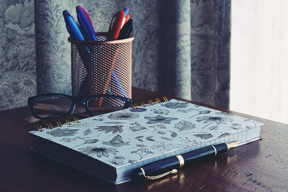 Quaderno e penne su una scrivania vicino alla finestra