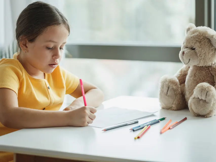 Bambina che disegna al tavolo del doposcuola