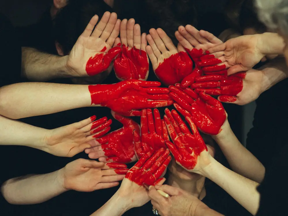 Mani dipinte di rosso che formano un cuore