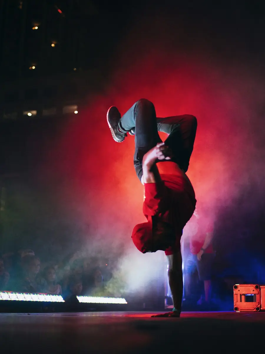 Ballerino di breakdance in equilibrio su una mano sotto le luci rosse