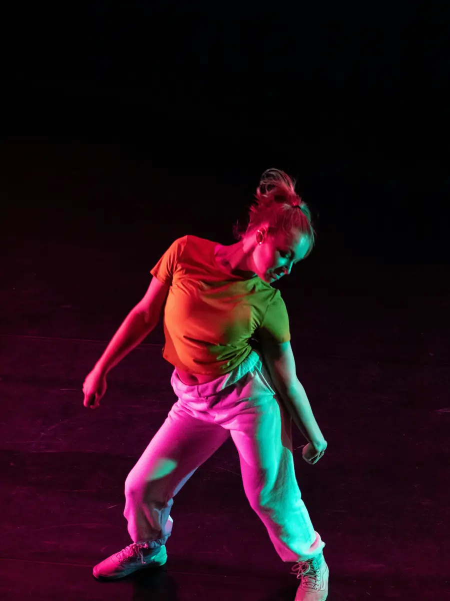 Ragazza che balla sotto una luce rosa e verde
