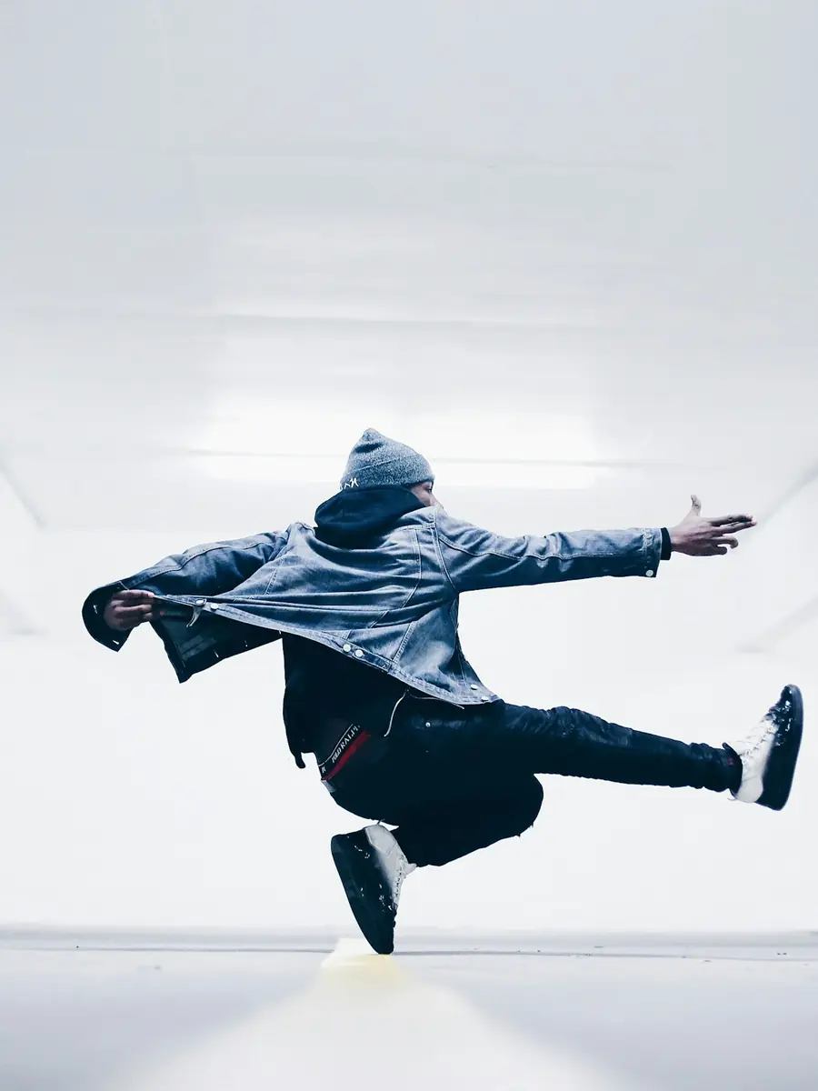 Ballerino con la felpa in un salto in un corridoio bianco