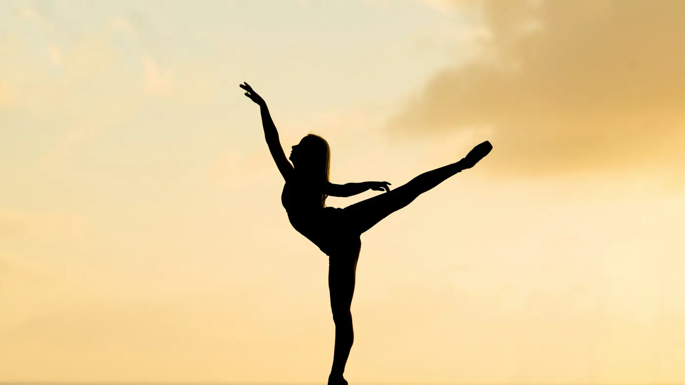Silhouette di una ballerina in arabesque al tramonto