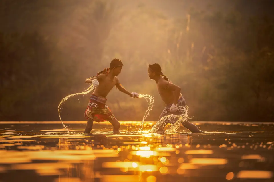 Due atleti di muay thai si affrontano nell'acqua bassa al tramonto