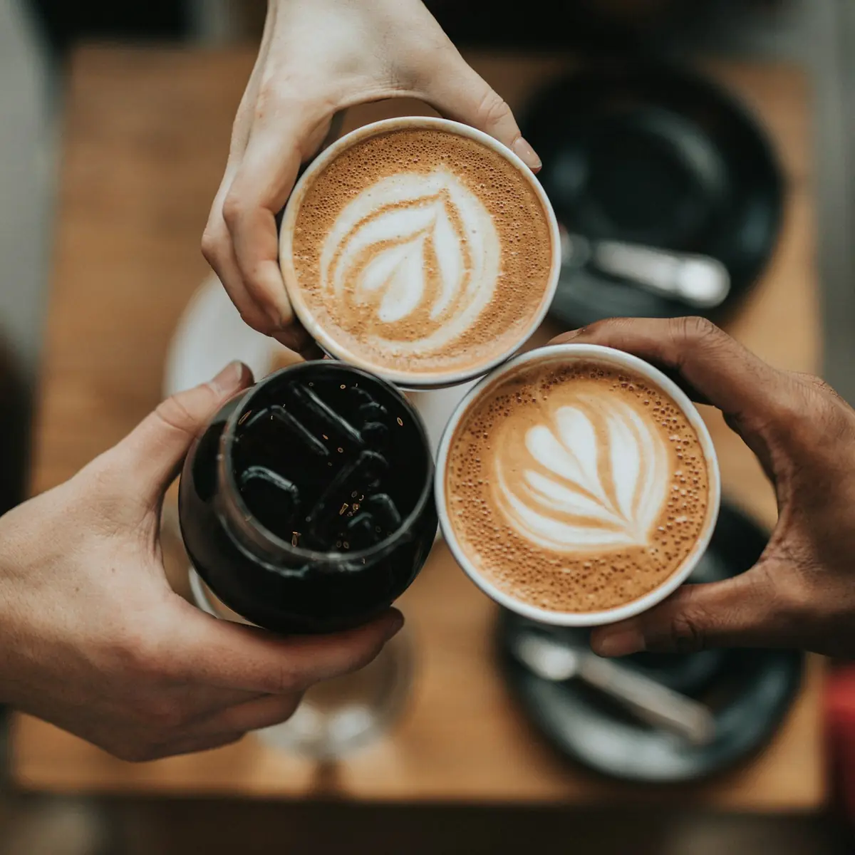 Tre tazze di caffè con la latte art che si toccano