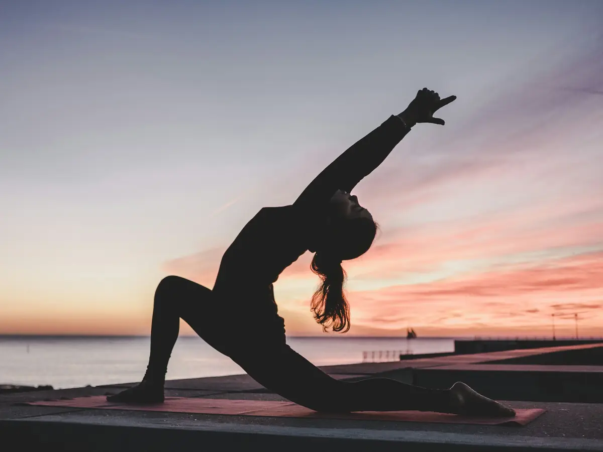 Ragazza che fa yoga sulla spiaggia al tramonto
